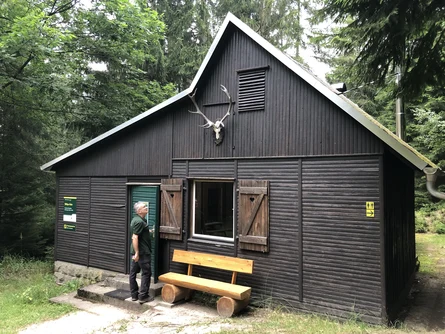 Ein Mann steht an einer Hütte im Wald.