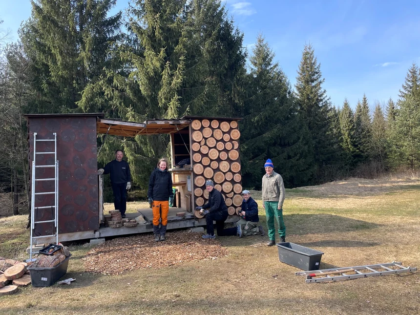 Fünf Personen setzen eine Wanderunterkunft instand und lachen in die Kamera.