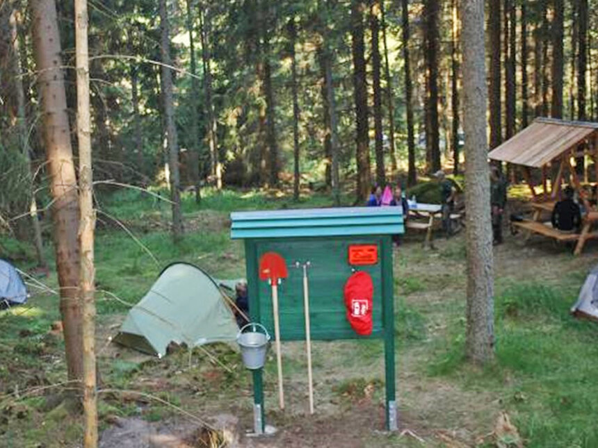 Waldlichtung mit Zelten und Sitzgelegenheit